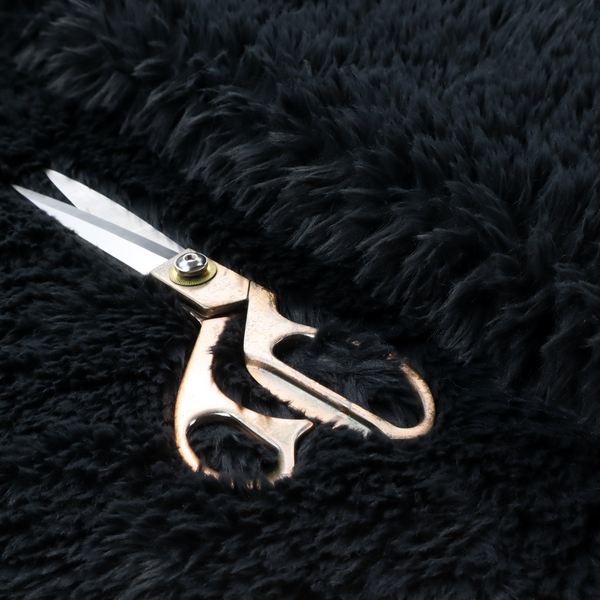 a solid black, high-pile faux fur fabric. It displays a dense, luxurious texture with soft, tousled fibres that create a cosy, sophisticated, and uniform shag-like appearance.