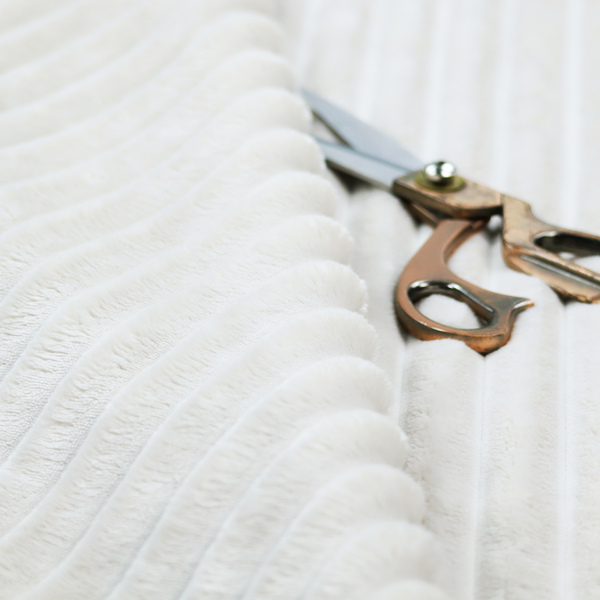 A cream-coloured textile featuring a repeating, vertical ribbed pattern. The fabric alternates between wide, soft, faux-fur-like plush bands and narrow, smooth, flat channels.