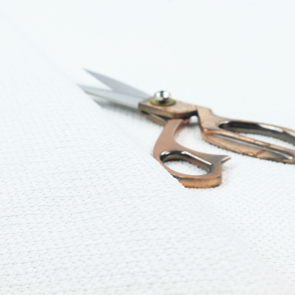 A white, textured fabric with a dense, rhythmic pattern. The material features a honeycomb or waffle-weave structure, where small, uniform raised circles create a grid-like tactile surface. The colour is a bright, cool-toned white, and the subtle shadows within the weave give the fabric a soft, multidimensional appearance.