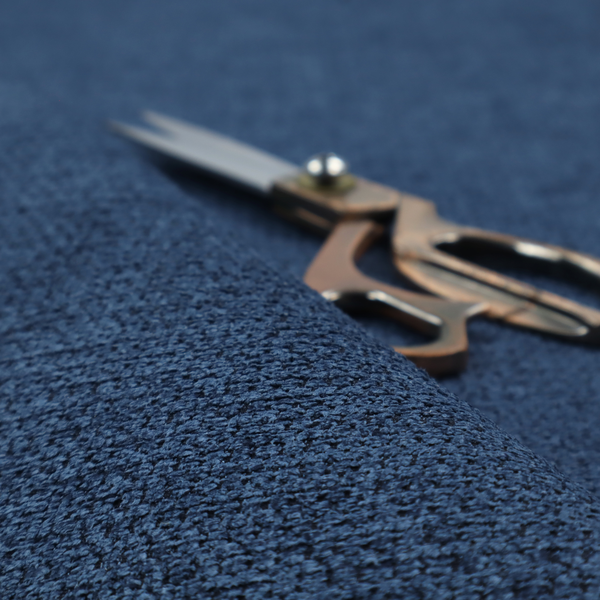 A textured fabric in a deep navy or midnight blue tone. The material features a dense, rhythmic weave with a prominent tactile surface. The colour is a rich, saturated indigo, achieved by interlacing vibrant blue threads with darker charcoal base fibres, creating a sophisticated, shadowed depth throughout the honeycomb-like pattern.