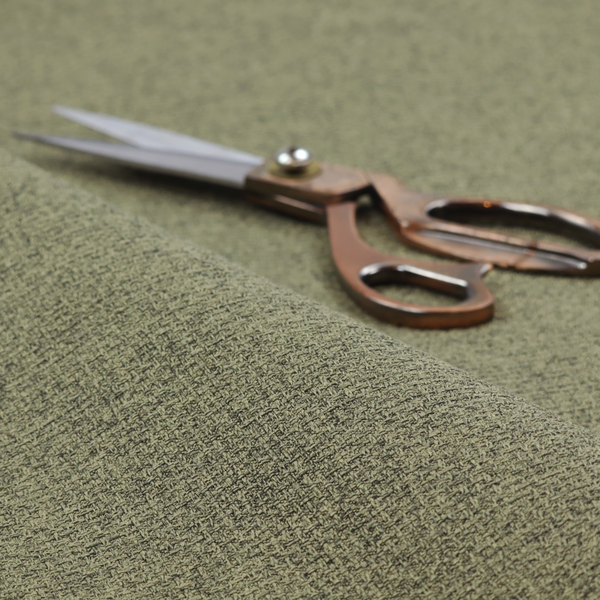 An upholstery fabric in an earthy olive or moss green shade. The textile features a dense, multi-tonal weave with interlaced threads of forest green, sage, and dark charcoal, creating a rich, textured linen-look surface with a matte finish.