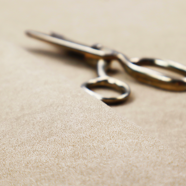 A warm beige or tan fabric with a dense, felt-like or distressed texture. The material features a fine, mottled pattern where sandy brown fibres mix with ivory highlights. Subtle, irregular horizontal "veining" or crackle lines run across the surface, giving it an organic, lived-in look similar to soft suede or pressed wool.