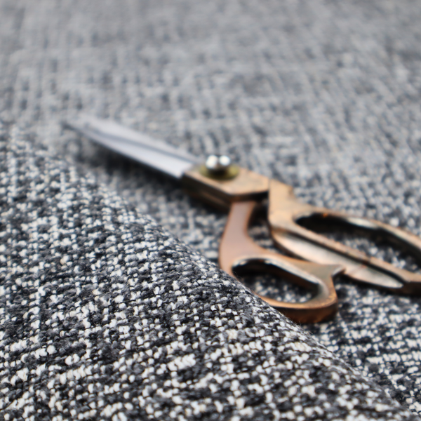 A dark, heavyweight woven fabric with a charcoal and slate-grey salt-and-pepper pattern. The dense bouclé weave creates a highly textured, pebbled surface with subtle off-white specks.