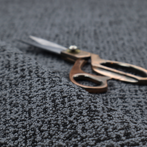 A dark, heavyweight woven fabric with a deep slate and charcoal marl pattern. The dense bouclé weave creates a low-contrast, pebbled texture with a uniform, dark grey appearance.