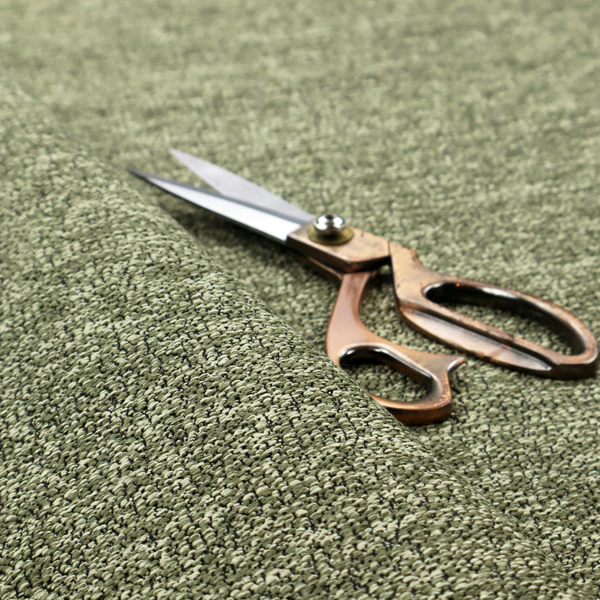 A sage green textured fabric with a dense, irregular black speckled pattern.
