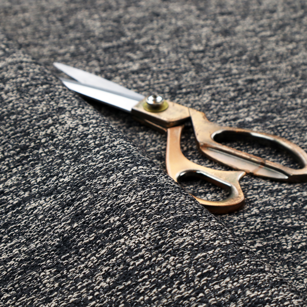 A black textured fabric with a dense, irregular cream and grey speckled pattern.