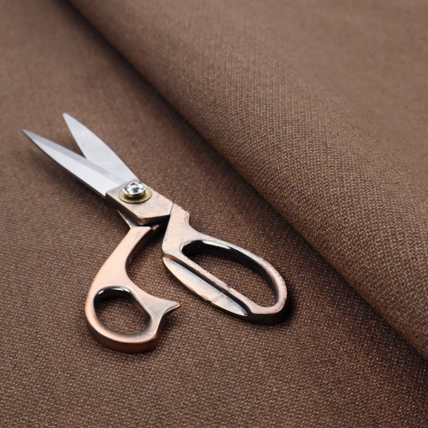 a dark chocolate or mocha brown textile with a tight diagonal twill weave. The fabric is woven with a deep brown base interspersed with fine, lighter threads that create a subtle shimmering or "salt and pepper" effect across the surface.