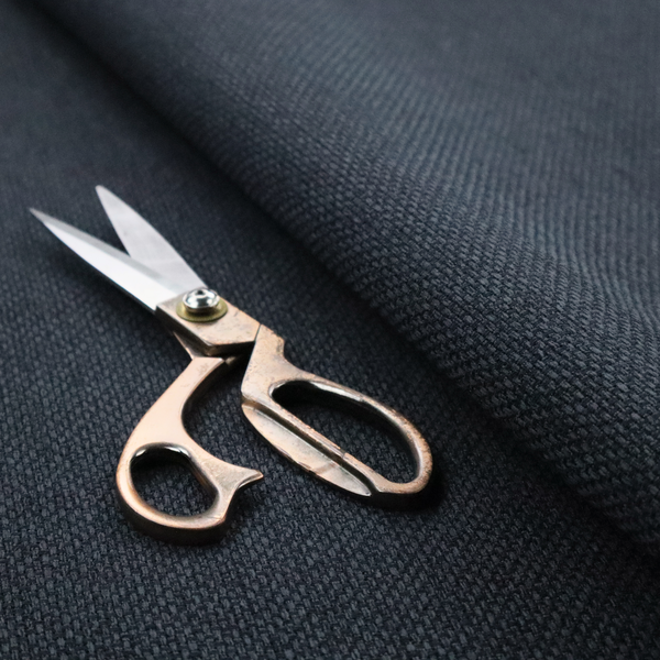 A dark charcoal-grey or slate fabric featuring a distinct, tightly woven grid texture. The material showcases a rich, multi-tonal, basket-weave style pattern with blended deep grey, subtle navy, and black threads, creating a moody, sophisticated, and matte finish across the entire surface.
