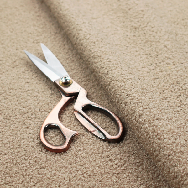 A textured khaki or warm taupe bouclé upholstery fabric.