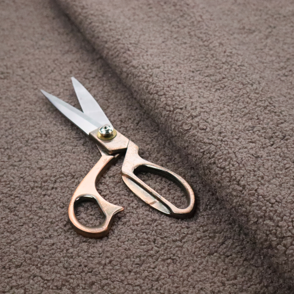 A textured rosy-brown or mauve bouclé upholstery fabric.