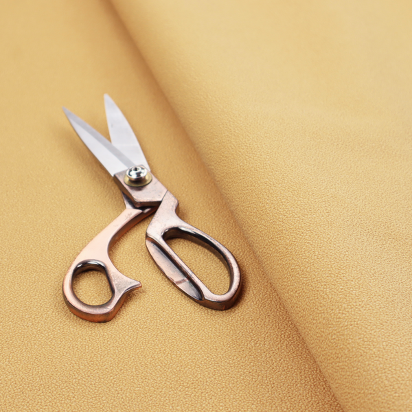 A warm ochre or golden yellow Merida Suede upholstery fabric. The textile features a highly detailed, dense, and uniform embossed pebbled pattern, giving the soft suede material an intricate, tactile shagreen texture.