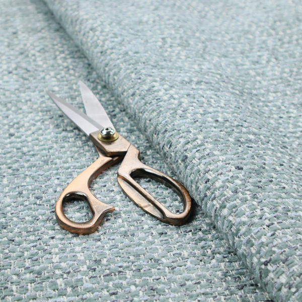 The material features a dense, multi-toned weave with a soft duck egg blue and sage green base, intricately interlaced with horizontal flecks of cream and muted slate grey threads throughout.