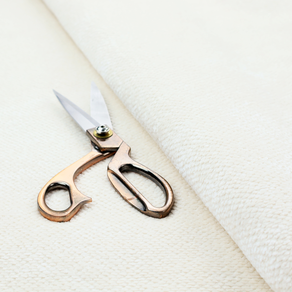 This image shows a close-up, high-resolution texture of a cream or off-white fabric. The material features a dense, uniform, boucle-style weave, characterized by small, looped, and nubby yarn fibres that create a soft, textured surface appearance.