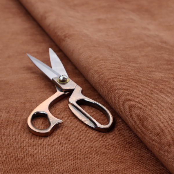 A textured, rich rust or burnt orange woven upholstery fabric.