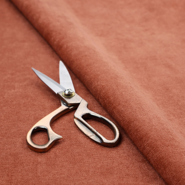 A textured, vibrant burnt orange or coral-coloured woven upholstery fabric.