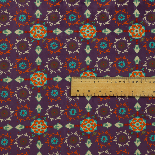 Geometric pattern fabric featuring a purple background with repeating orange and teal mandala-style floral motifs.