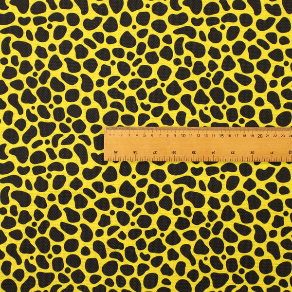 A bold cheetah-style animal print featuring irregular, black organic spots scattered across a bright canary yellow background.