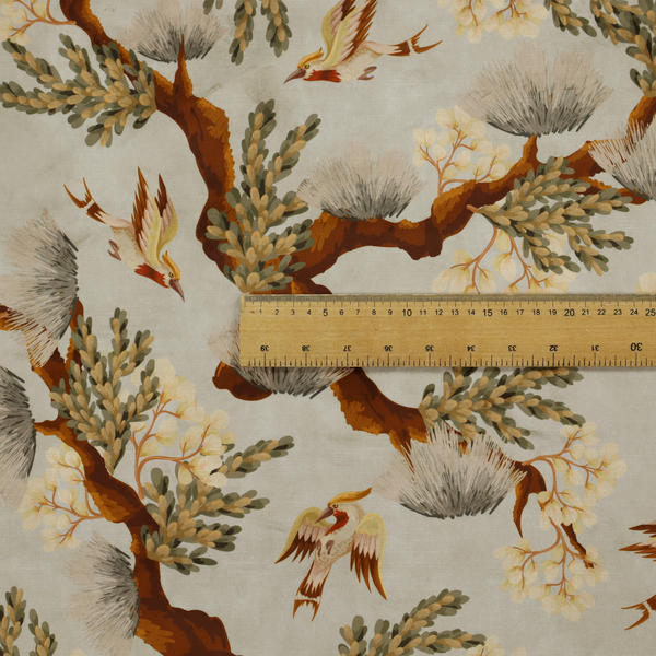 A sophisticated textile featuring a Chinoiserie-style pattern with stylized birds in flight among winding, dark brown tree branches. The branches are adorned with clusters of pale cream blossoms and soft, pine-like needles. The entire design is set against a muted beige background creating a serene and classical aesthetic.