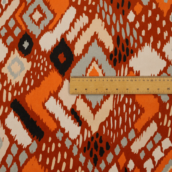 Bohemian ikat fabric featuring a dense diamond pattern in burnt orange, cream, and charcoal black with distressed, hand-stamped textures.