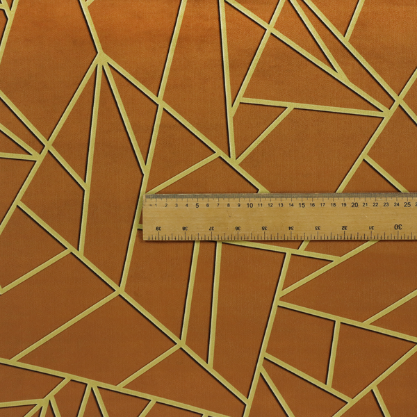 A close-up of a luxurious brown or rust-coloured fabric featuring a fractured, geometric mosaic pattern. The warm, matte background is divided by a network of recessed gold metallic lines that form sharp, irregular polygons. This "cracked ice" or shattered-glass effect creates a bold, architectural look, blending the deep, earthy tones of the textile with shimmering, Art Deco-inspired accents.