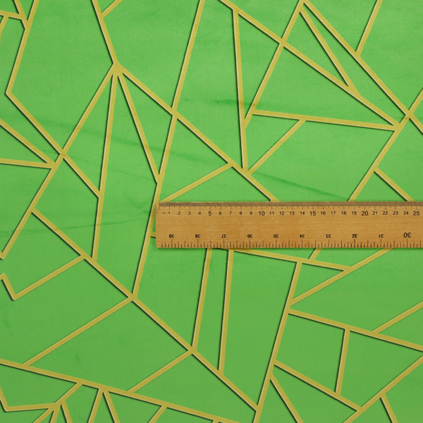 A close-up of a vibrant bright green fabric featuring a fractured, geometric mosaic pattern. The lively, matte background is segmented by a network of recessed metallic gold lines that form sharp, irregular polygons. This "cracked ice" or shattered-glass effect creates a bold, modern look, combining a lush, verdant base with shimmering, Art Deco-inspired accents.