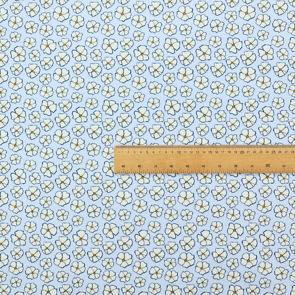 A light blue fabric featuring a dense, repeating pattern of small white flowers with yellow centres and dark outlines.
