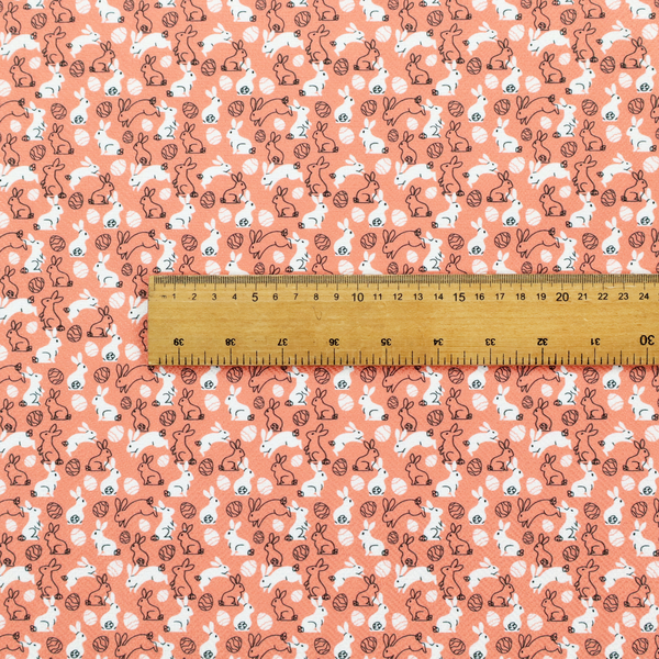 This fabric features a graphic, contemporary Easter pattern set against a warm, terracotta-orange background. The design is characterized by its clean, high-contrast motifs and a limited, modern colour palette.