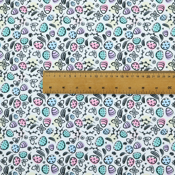 This fabric features an artistic, hand-illustrated Easter egg pattern on a cool, pale blue background. The design has a sketchbook or "doodle" quality, with expressive black ink outlines and soft watercolour-style colour accents.