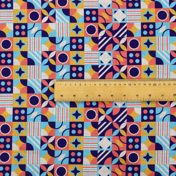 A high-energy, multi-coloured geometric fabric featuring a rhythmic grid of Bauhaus-inspired motifs. The design is a playful mosaic of circles, stars, stripes, and quarter-moons in a vibrant palette of mustard yellow, coral pink, sky blue, and deep midnight navy, all set against a textured, off-white linen-look background.