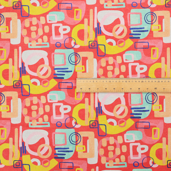 A vibrant fabric print featuring an abstract, mid-century modern design. The pattern consists of overlapping geometric shapes—circles, rectangles, and arches—in a lively palette of coral, bright yellow, teal, and soft peach on a coral-red background, creating a playful and retro aesthetic.