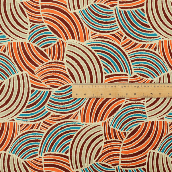 This fabric features a geometric, fan-like pattern composed of overlapping semi-circular arcs. The design creates a dynamic sense of movement through a vibrant colour palette of burnt orange, deep brown, bright turquoise, and cream.