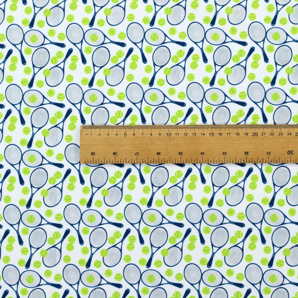 A white fabric featuring a vibrant, repeating pattern of tennis rackets and tennis balls.
