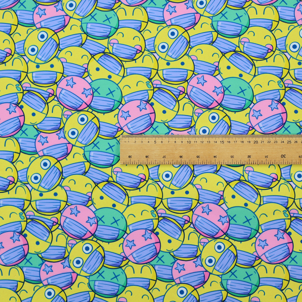 Seamless novelty fabric pattern featuring a dense, overlapping collage of cartoon emoji smiley faces wearing blue face masks in bright neon yellow, green, and pink.