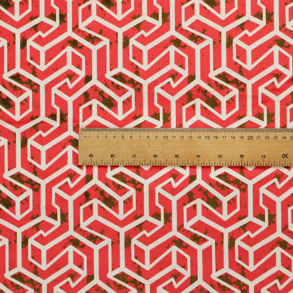A red and off-white textile fabric featuring a repeating, interlocking geometric pattern. The design consists of off-white outlines forming three-dimensional, isometric maze-like structures against a vibrant coral red background. Distressed, dark brown speckled textures are subtly scattered throughout the red spaces, adding a weathered, organic touch to the structured, geometric design.