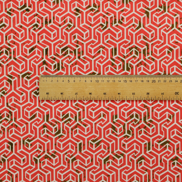 A coral red and off-white textile fabric featuring a small-scale, densely repeating interlocking geometric pattern. Fine off-white outlines construct complex, three-dimensional isometric block formations against a vibrant coral red background. Distressed, dark brown speckled textures are integrated throughout, creating a weathered, organic contrast to the sharp geometric structure.