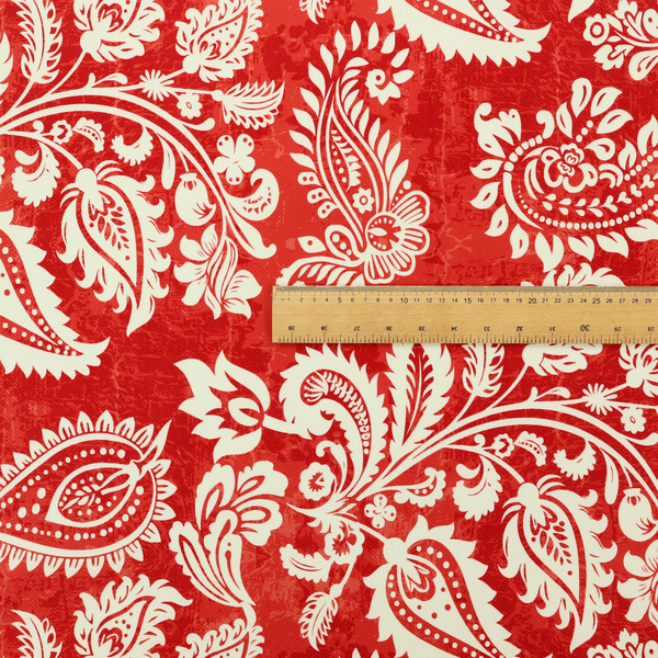 Fabric featuring an ornate repeating pattern of elegant ivory paisley motifs and botanical flourishes over a textured, mottled crimson red background.