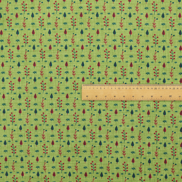 A green upholstery fabric featuring a ditsy folk-art pattern of small red berries, sprigs, and dark blue leaves.