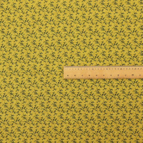 Mustard yellow fabric featuring a dense, repeating pattern of small dark green or black trailing vines with tiny leaves and a subtle woven texture.