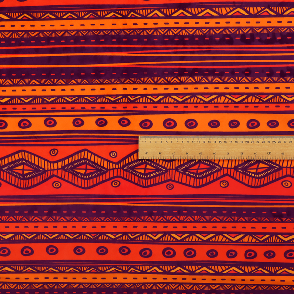 A vibrant orange and red fabric featuring a repeating tribal geometric and striped pattern.