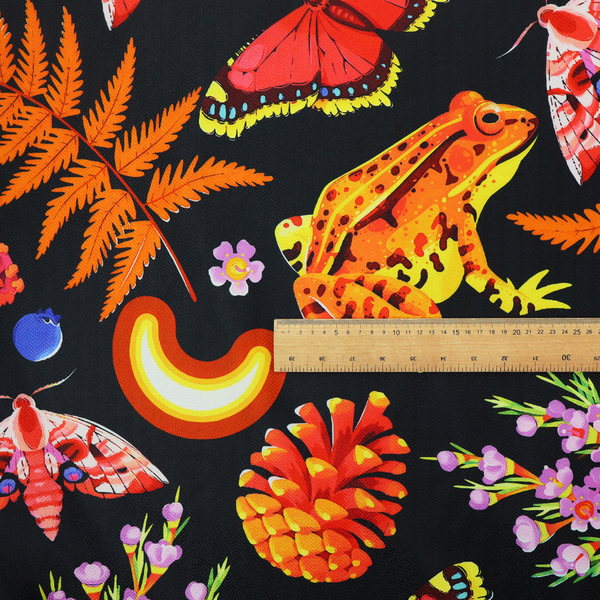 A vibrant, repeating botanical pattern on a black background featuring bright red butterflies, orange spotted frogs, orange pinecones, pink and white mushrooms, orange fern fronds, blue berries, and purple wildflowers.