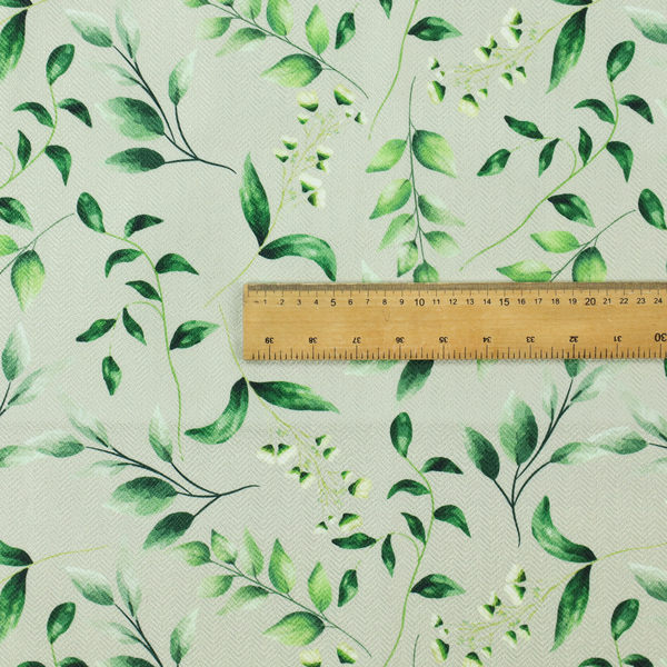 Watercolour botanical fabric featuring a repeating pattern of leafy green branches and delicate white blossoms on a light sage-grey twill background.