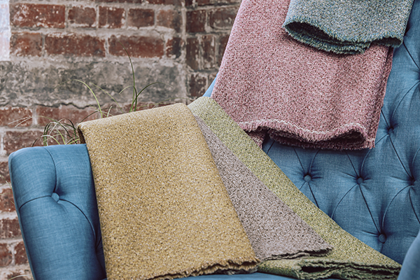 An image of upholstery fabrics, draped across a blue arm chair.