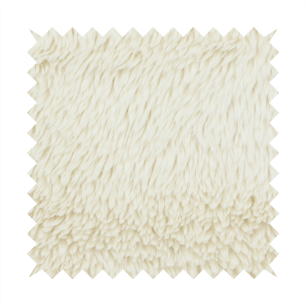 A cream or off-white, high-pile faux fur fabric. The texture appears soft, fluffy, and dense, characterized by long, slightly tousled fibres that give it a cosy, shag-like appearance.