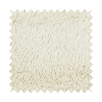 A cream or off-white, high-pile faux fur fabric. The texture appears soft, fluffy, and dense, characterized by long, slightly tousled fibres that give it a cosy, shag-like appearance.