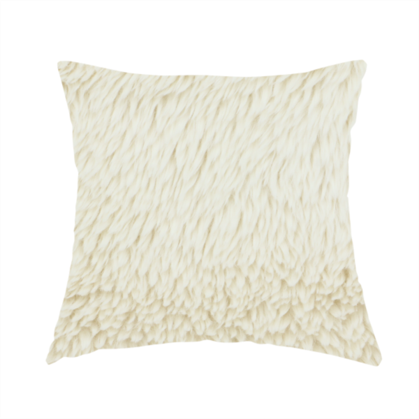 The fabric used to create this handmade cushion is a cream or off-white, high-pile faux fur fabric. The texture appears soft, fluffy, and dense, characterized by long, slightly tousled fibres that give it a cosy, shag-like appearance.