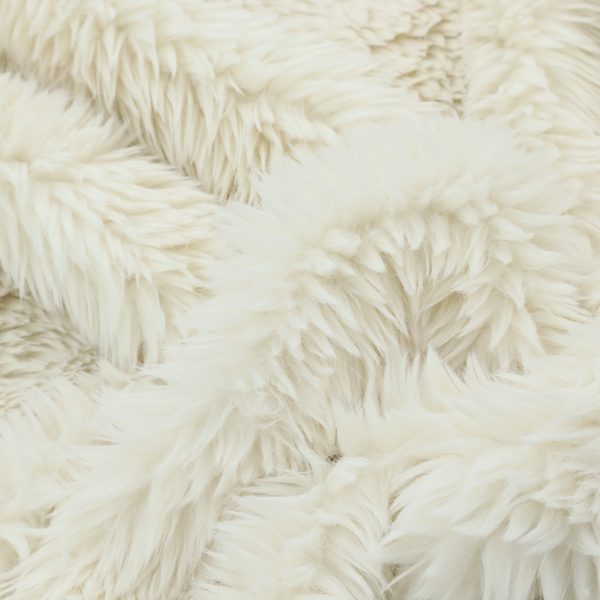 A cream or off-white, high-pile faux fur fabric. The texture appears soft, fluffy, and dense, characterized by long, slightly tousled fibres that give it a cosy, shag-like appearance.