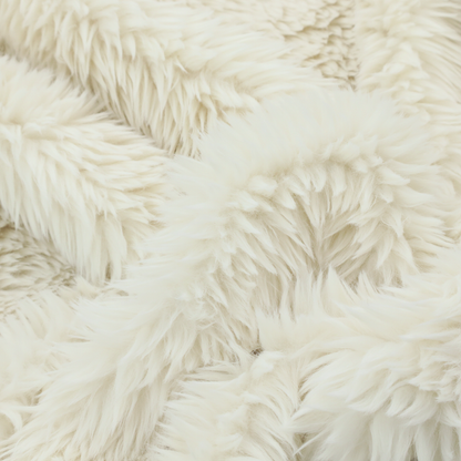 A cream or off-white, high-pile faux fur fabric. The texture appears soft, fluffy, and dense, characterized by long, slightly tousled fibres that give it a cosy, shag-like appearance.