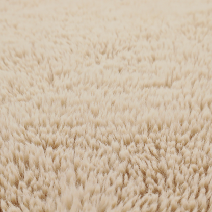 A tan or light beige, high-pile faux fur fabric. It has a dense, plush, and cosy texture with soft, slightly tousled fibres that create a shag-like appearance.