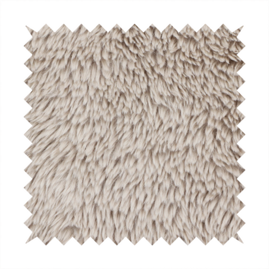 A taupe or light greyish-brown, high-pile faux fur fabric. It features a dense, plush texture with soft, tousled fibres that create a cosy, shag-like appearance.