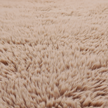 A warm beige or sandy-toned, high-pile faux fur fabric. It displays a dense, luxurious texture with soft, tousled fibres that create a cosy, shag-inspired look.